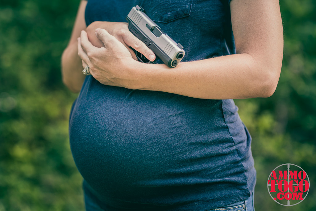a photo of a woman shooting while pregnant outdoors with a glock 48 pistol