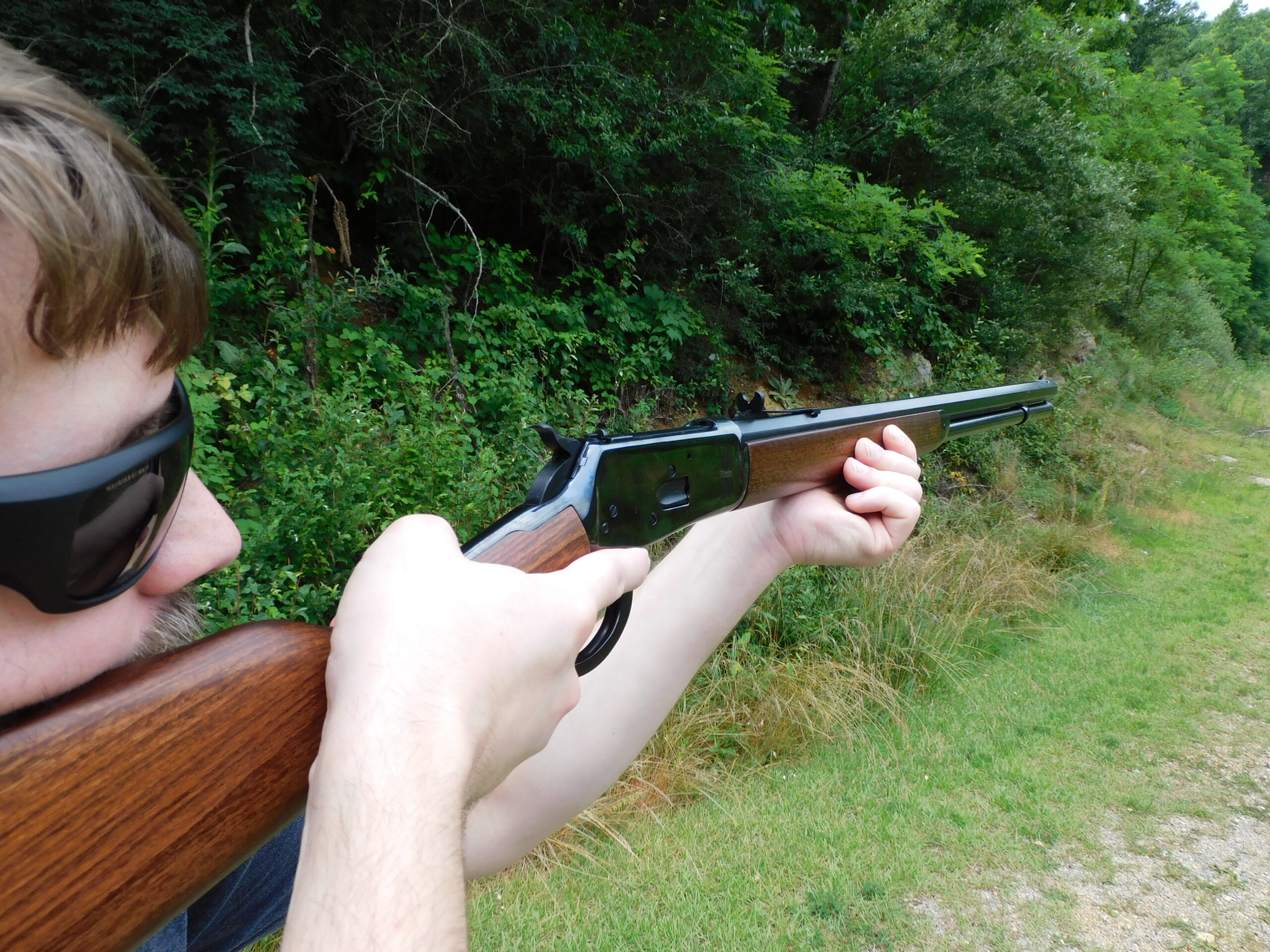 The co-tester firing the Heritage lever action at the range Rear three-quarter view of shooter aiming Heritage 92 lever action showing receiver and rear sight