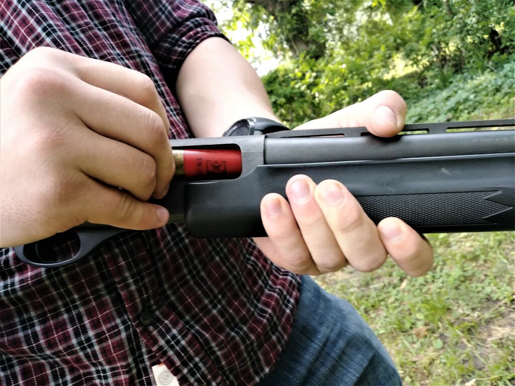 loading a shotshell into a shotgun chamber