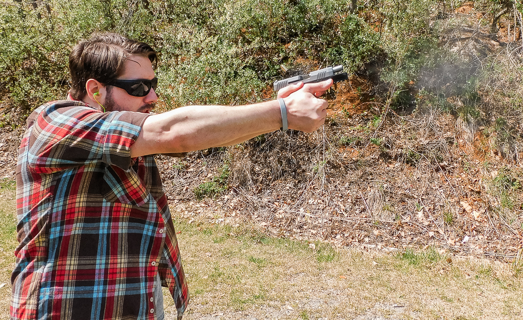 The author firing Taurus GX2 with visible recoil at an outdoor shooting range.